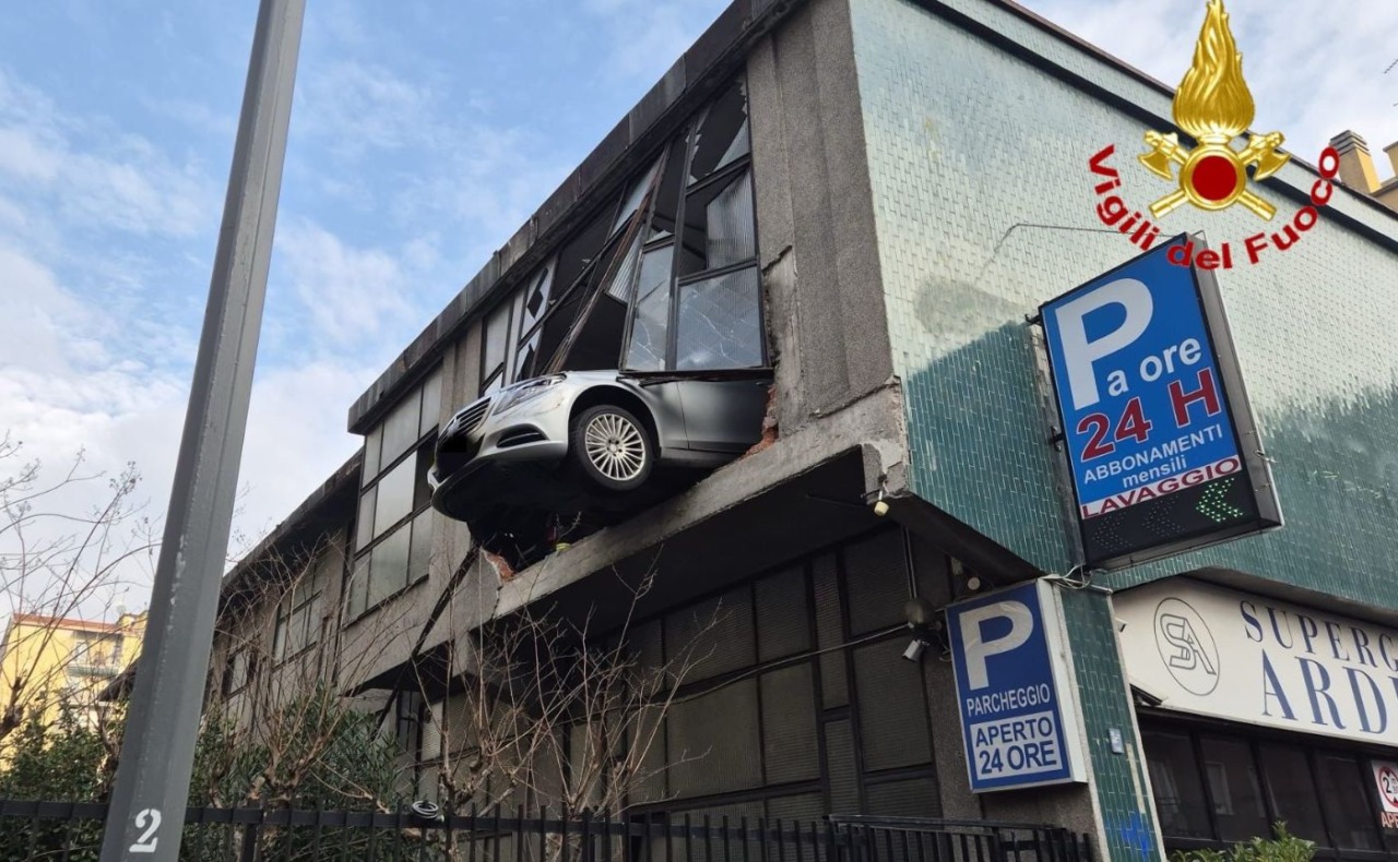 Perde il controllo dell’auto in un garage multipiano e sfonda il vetro: la vettura resta sospesa nel vuoto a otto metri di altezza