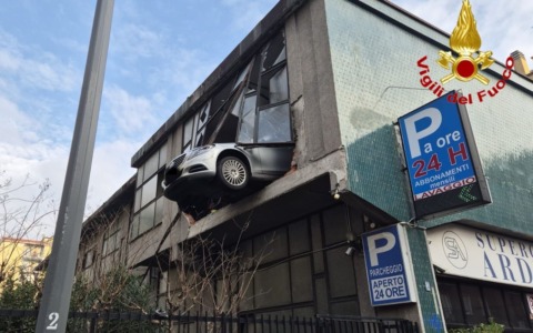 Perde il controllo dell’auto in un garage multipiano e sfonda il vetro: la vettura resta sospesa nel vuoto a otto metri di altezza